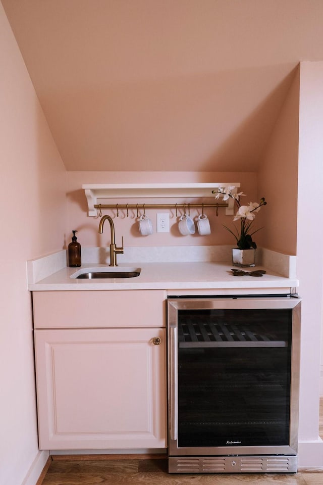 bar with wine cooler, vaulted ceiling, sink, and white cabinets