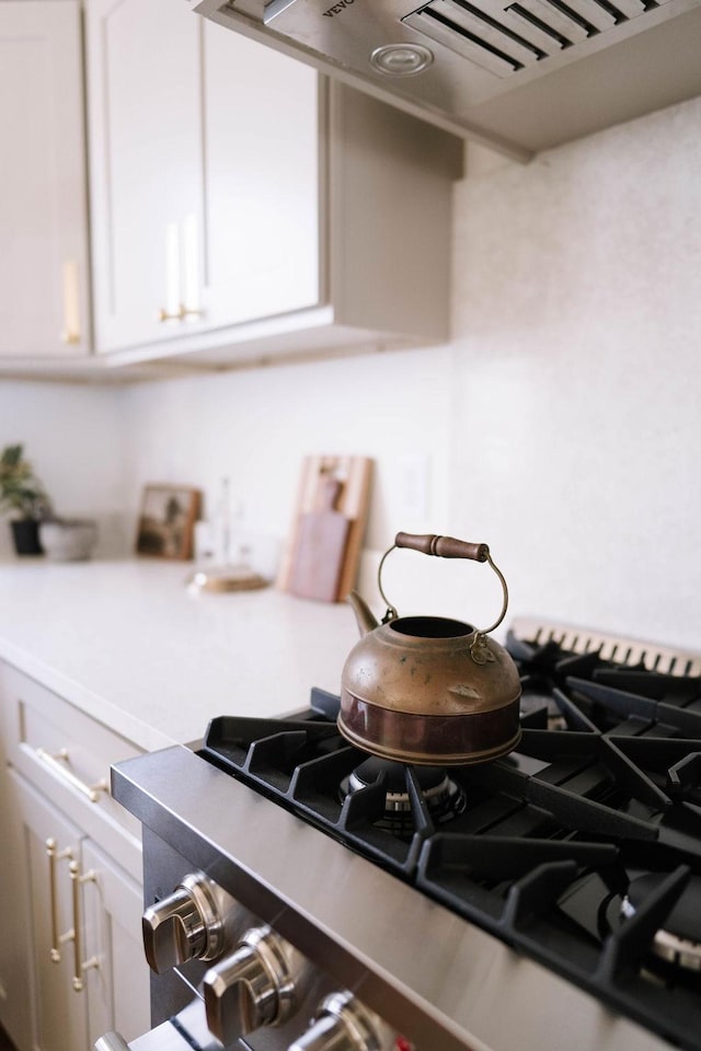 interior space featuring dark stone countertops, white cabinets, cooktop, and wall chimney exhaust hood