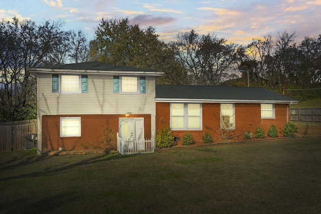 view of front of property featuring central air condition unit and a lawn