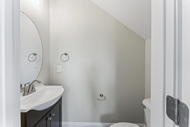 bathroom featuring vanity, toilet, and vaulted ceiling