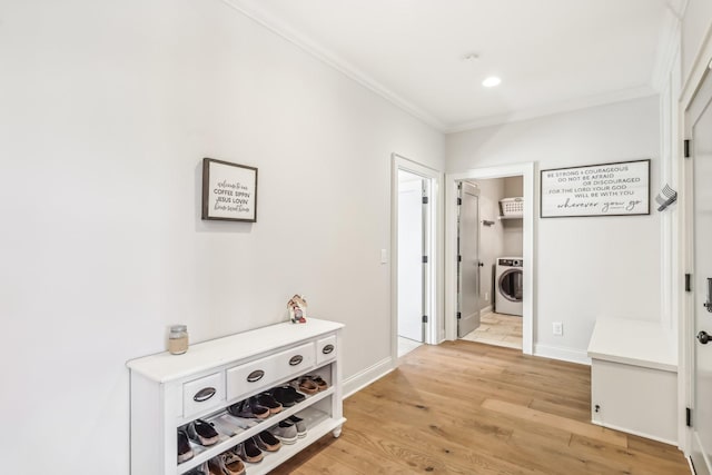 corridor with light wood-type flooring, washer / clothes dryer, and ornamental molding