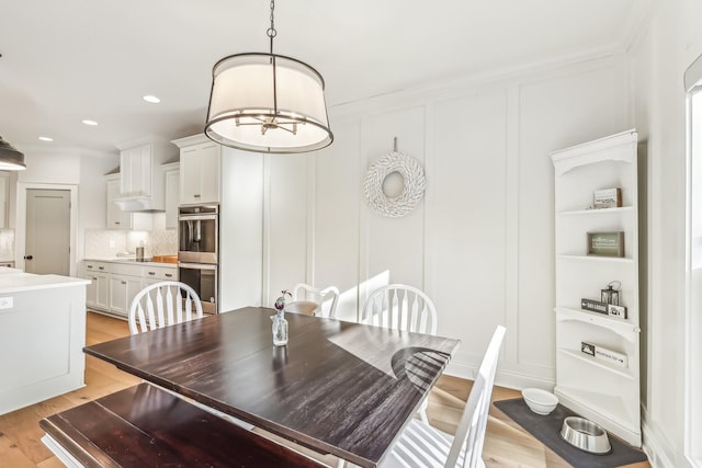 dining space featuring a chandelier, light hardwood / wood-style floors, built in features, and crown molding