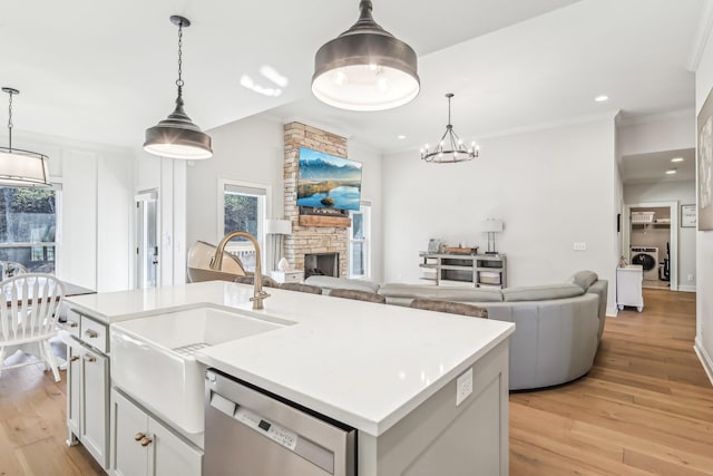 kitchen featuring stainless steel dishwasher, a kitchen island with sink, and hanging light fixtures