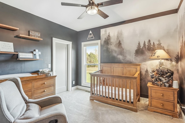 carpeted bedroom featuring ceiling fan and a nursery area