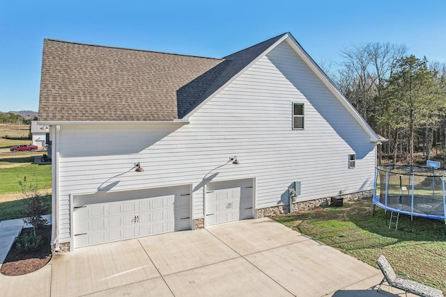 view of home's exterior with a lawn, a garage, a trampoline, and central AC