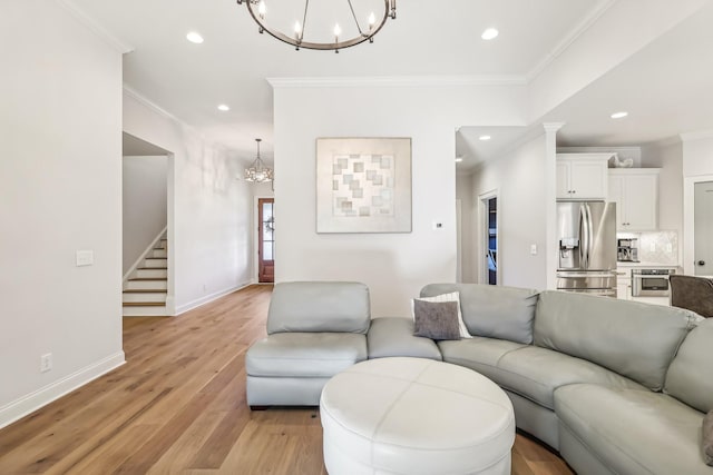 living room with light hardwood / wood-style flooring, an inviting chandelier, and ornamental molding