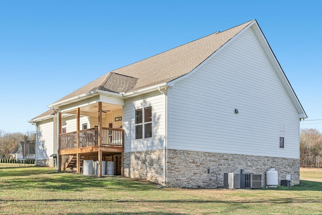 rear view of property with a yard, a trampoline, central AC unit, and ceiling fan