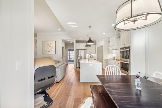 dining room with light hardwood / wood-style flooring, crown molding, and sink