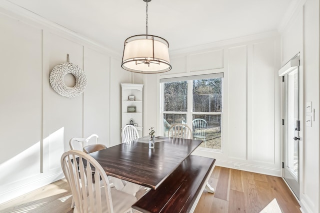 dining area with light hardwood / wood-style floors and ornamental molding