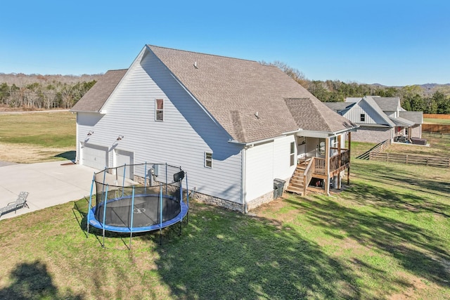 rear view of house with a lawn, a garage, and a trampoline