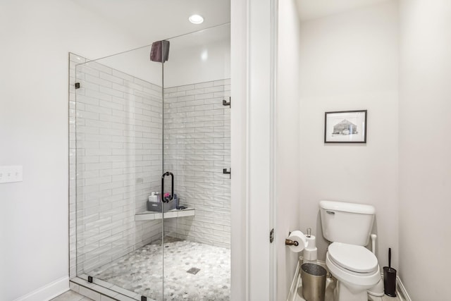 bathroom with tile patterned floors, toilet, and a shower with door