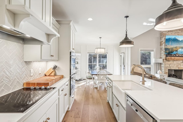 kitchen featuring sink, an island with sink, decorative light fixtures, appliances with stainless steel finishes, and light wood-type flooring