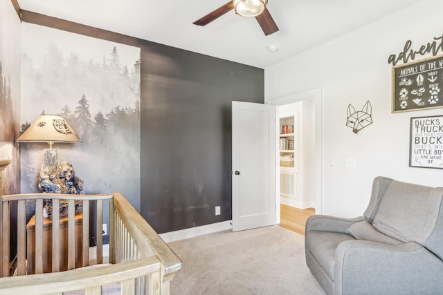 carpeted bedroom with ceiling fan and a nursery area