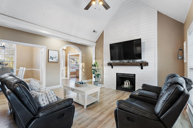 living room with ceiling fan, a fireplace, high vaulted ceiling, and light hardwood / wood-style flooring