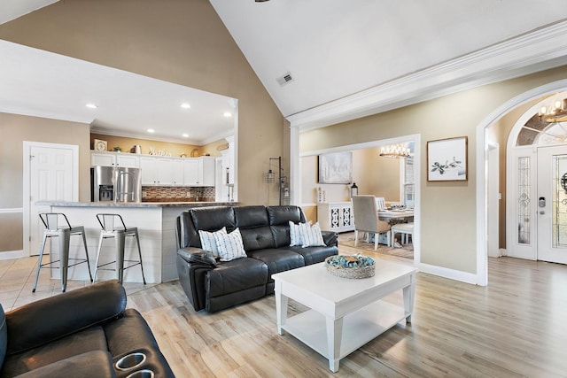 living room featuring light hardwood / wood-style floors, crown molding, high vaulted ceiling, and a chandelier