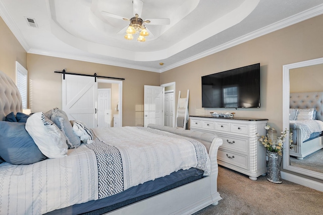 carpeted bedroom with a raised ceiling, a barn door, ceiling fan, and crown molding