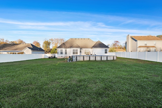 rear view of property with a fenced in pool and a yard