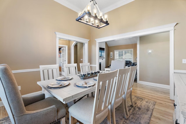 dining room with an inviting chandelier, ornamental molding, and light hardwood / wood-style flooring