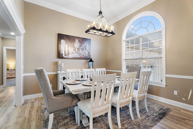 dining space with a notable chandelier, light wood-type flooring, and crown molding