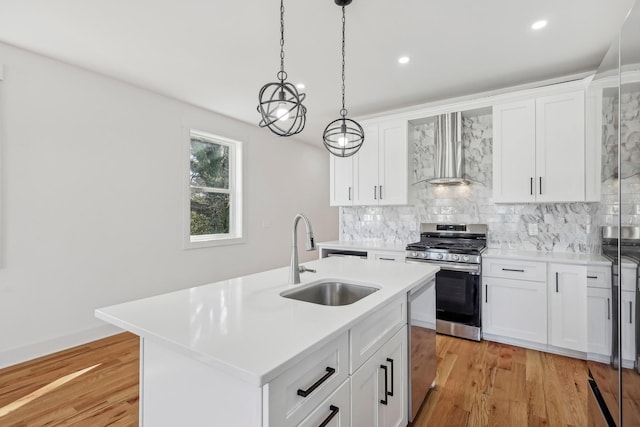 kitchen featuring sink, wall chimney range hood, a center island with sink, white cabinets, and appliances with stainless steel finishes