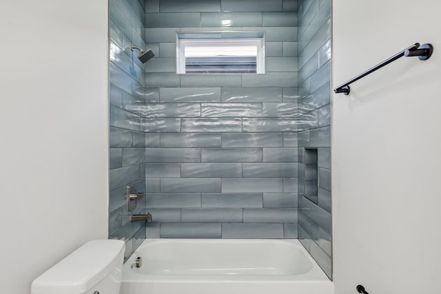 bathroom featuring tiled shower / bath combo and toilet