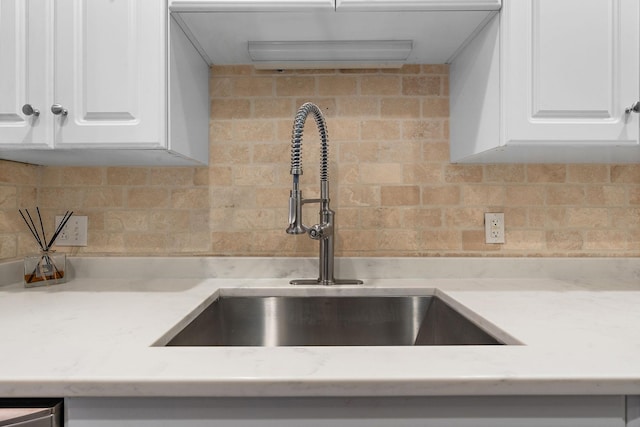 interior details with white cabinets, tasteful backsplash, and sink