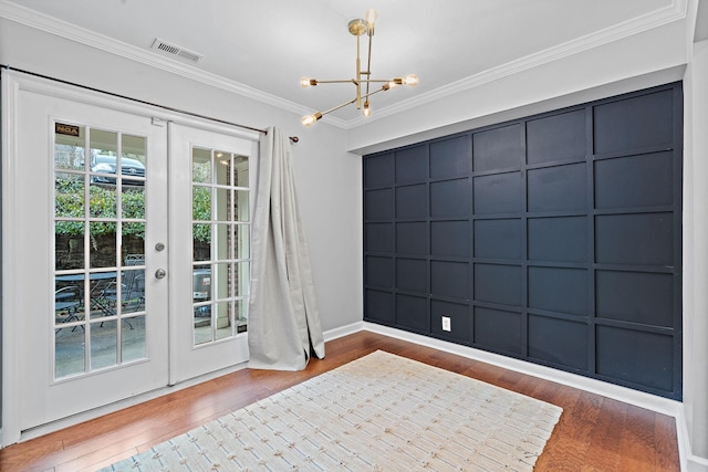 doorway to outside featuring french doors, wood-type flooring, ornamental molding, and an inviting chandelier