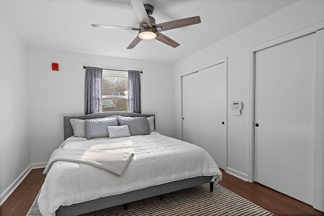 bedroom with two closets, ceiling fan, and dark hardwood / wood-style floors