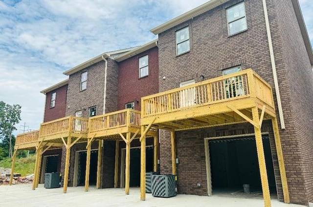 rear view of property with a garage, central air condition unit, and a wooden deck