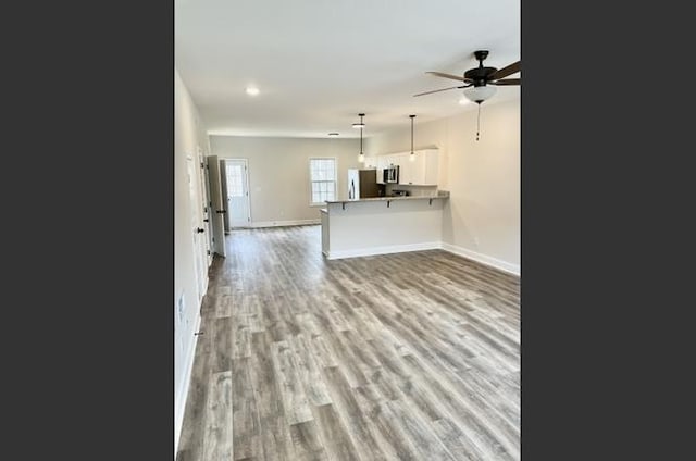 unfurnished living room featuring ceiling fan and light wood-type flooring