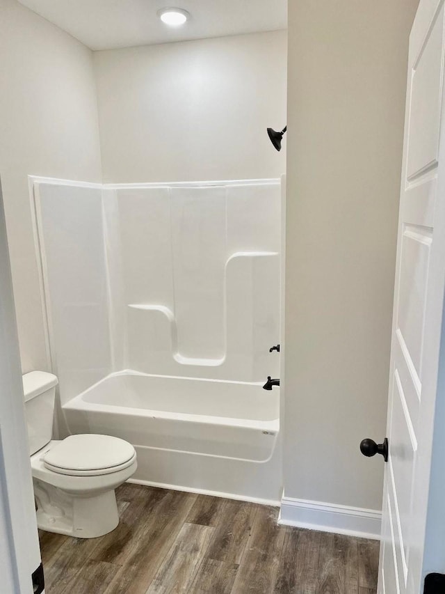 bathroom with wood-type flooring, toilet, and shower / bathtub combination