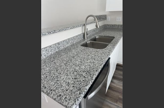 kitchen featuring light stone countertops, stainless steel dishwasher, sink, white cabinets, and dark hardwood / wood-style floors