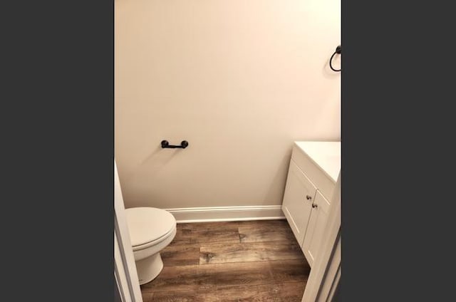 bathroom with wood-type flooring, vanity, and toilet