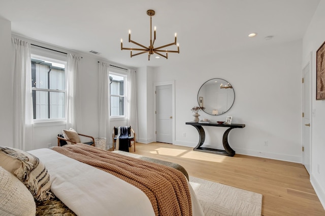 bedroom with an inviting chandelier and light hardwood / wood-style flooring