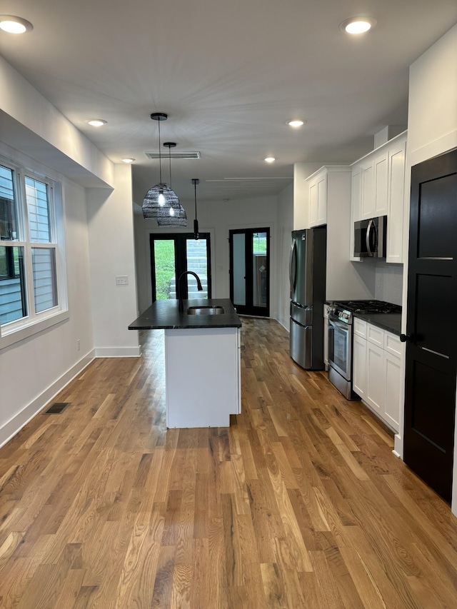 kitchen featuring plenty of natural light, decorative light fixtures, an island with sink, and appliances with stainless steel finishes