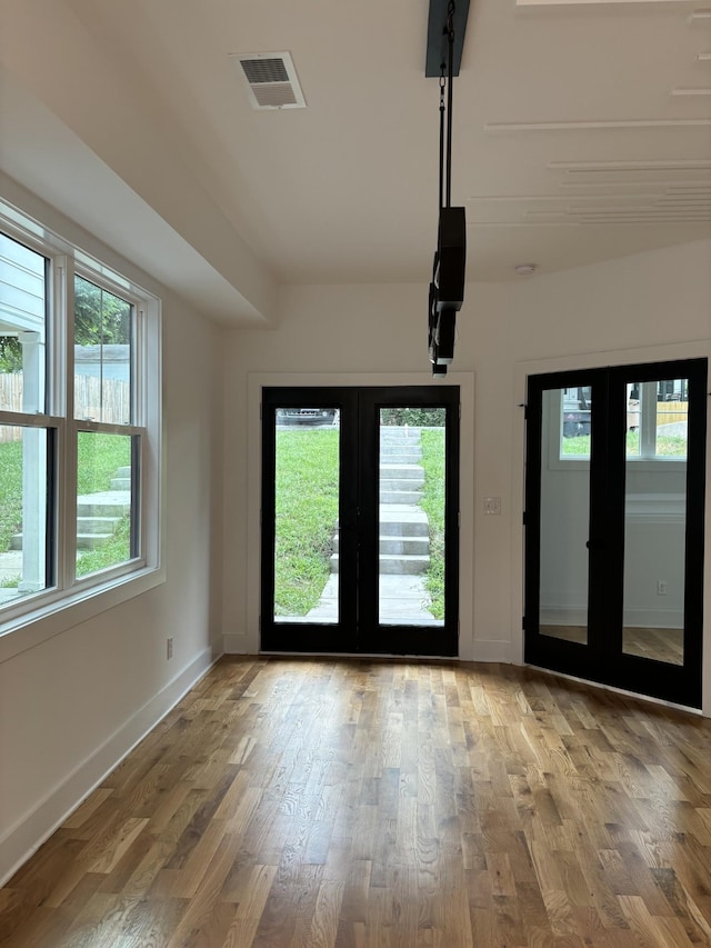 spare room with french doors, hardwood / wood-style flooring, and a healthy amount of sunlight