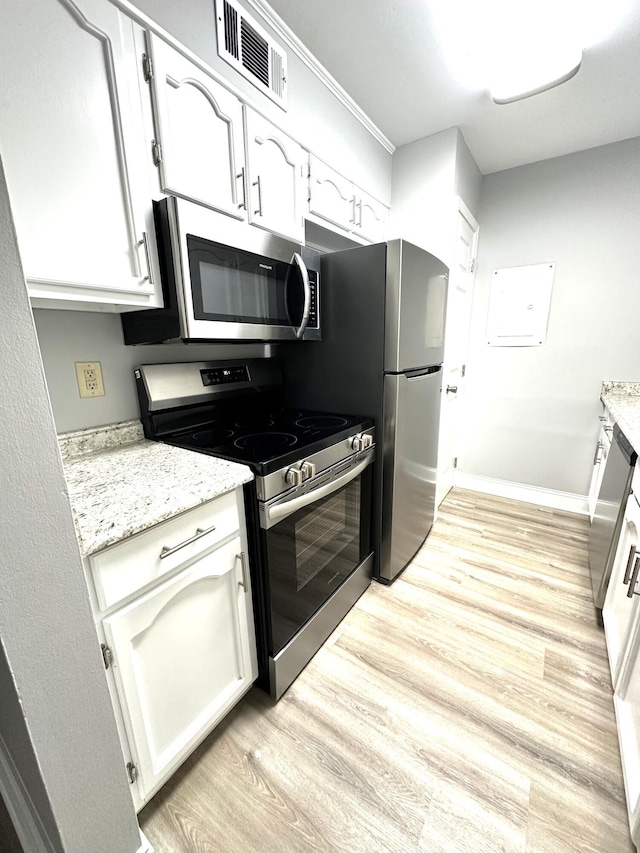 kitchen featuring light stone counters, appliances with stainless steel finishes, light wood-type flooring, and white cabinets