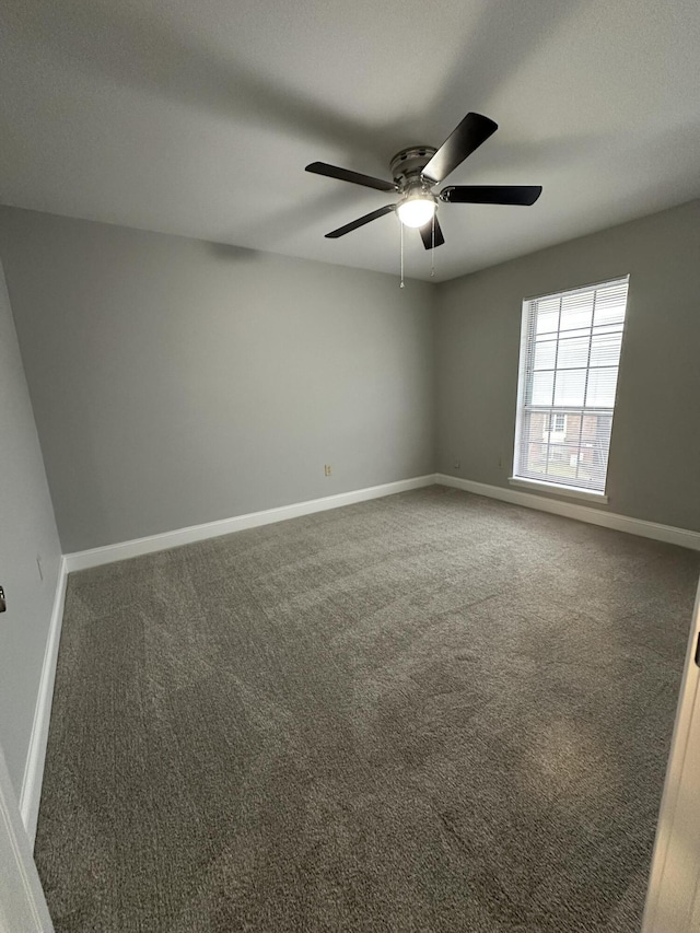 spare room with ceiling fan and dark colored carpet