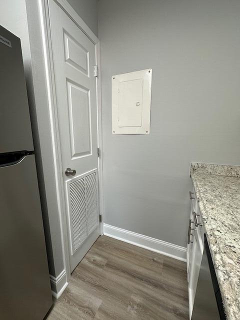 interior details with wood finished floors, electric panel, baseboards, visible vents, and freestanding refrigerator