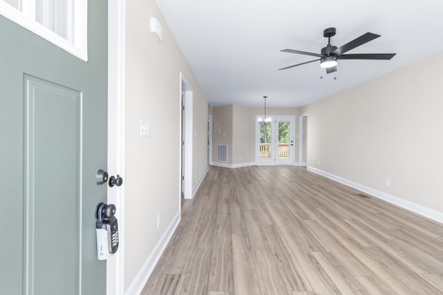 interior space featuring ceiling fan with notable chandelier and light hardwood / wood-style floors