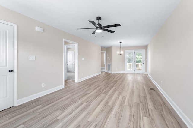 unfurnished living room featuring ceiling fan with notable chandelier and light hardwood / wood-style floors