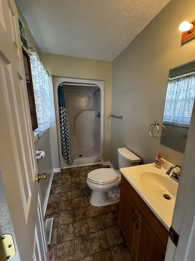 bathroom with toilet, vanity, a textured ceiling, and walk in shower