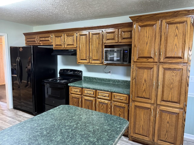 kitchen featuring black appliances, a textured ceiling, and light wood-type flooring