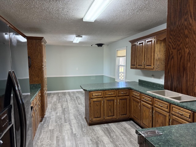 kitchen featuring stainless steel fridge with ice dispenser, kitchen peninsula, a textured ceiling, and light hardwood / wood-style flooring