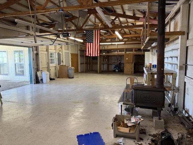 miscellaneous room with a wood stove, electric panel, and concrete floors