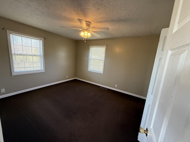 unfurnished room featuring ceiling fan, dark carpet, and a textured ceiling