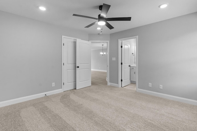 unfurnished bedroom with ensuite bathroom, ceiling fan with notable chandelier, and light carpet