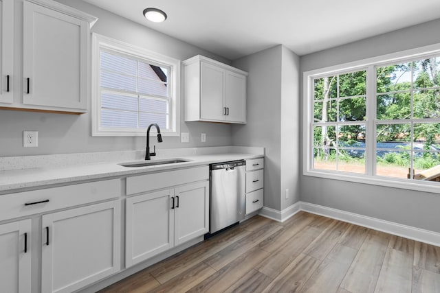 kitchen with dishwasher, white cabinets, light hardwood / wood-style flooring, and sink