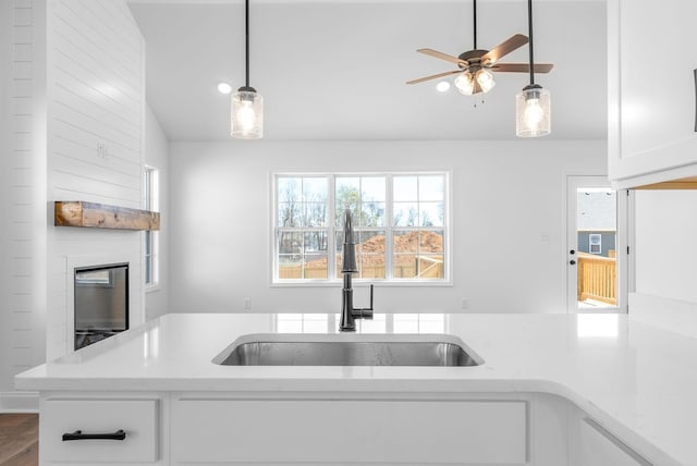 kitchen featuring light stone counters, sink, pendant lighting, hardwood / wood-style flooring, and white cabinetry