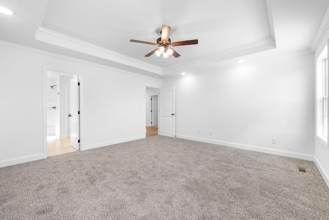 carpeted spare room featuring a tray ceiling, ceiling fan, and ornamental molding